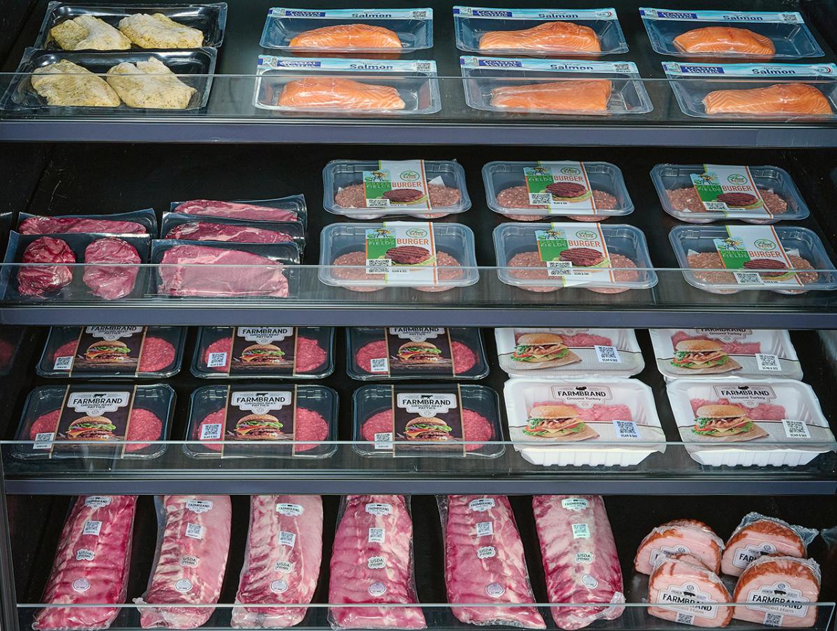SEE® Case-Ready Solutions Packages of various proteins including meat and fish sitting on shelves in a refrigerated grocery store case