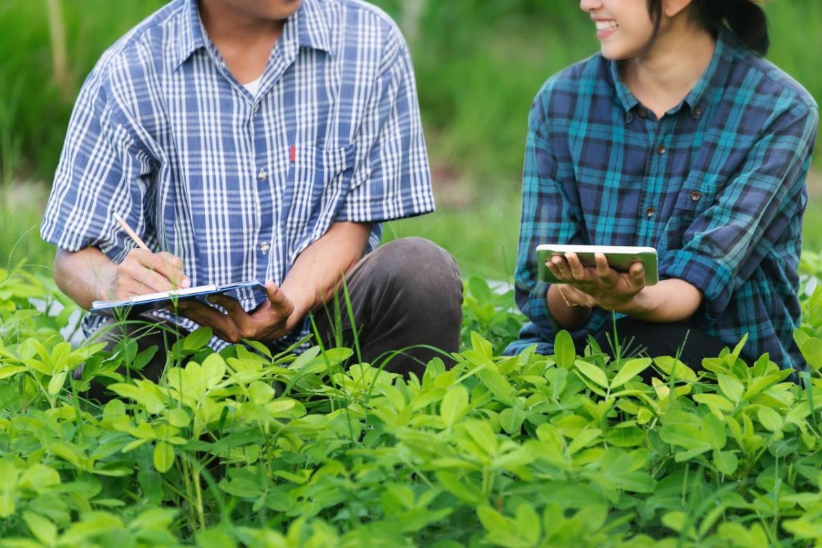 Two people in a farm holding tablets smiling at each other 