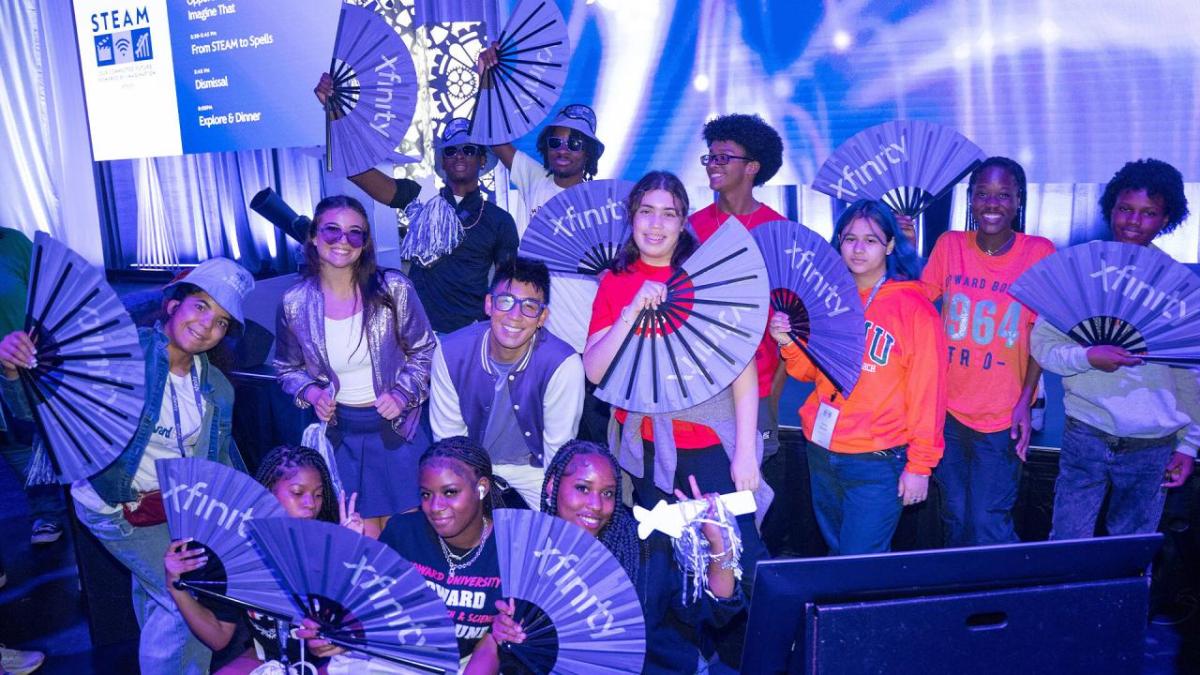 Students holding up purple fans with the xfinity logo