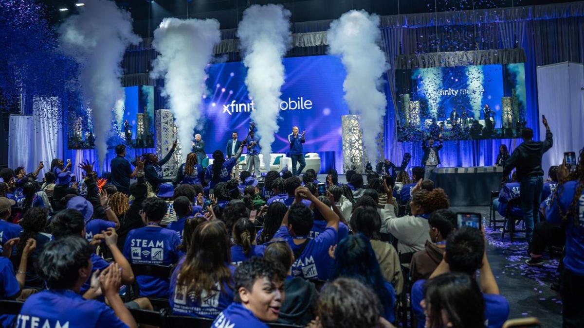 Students in audience watching people speaking on stage