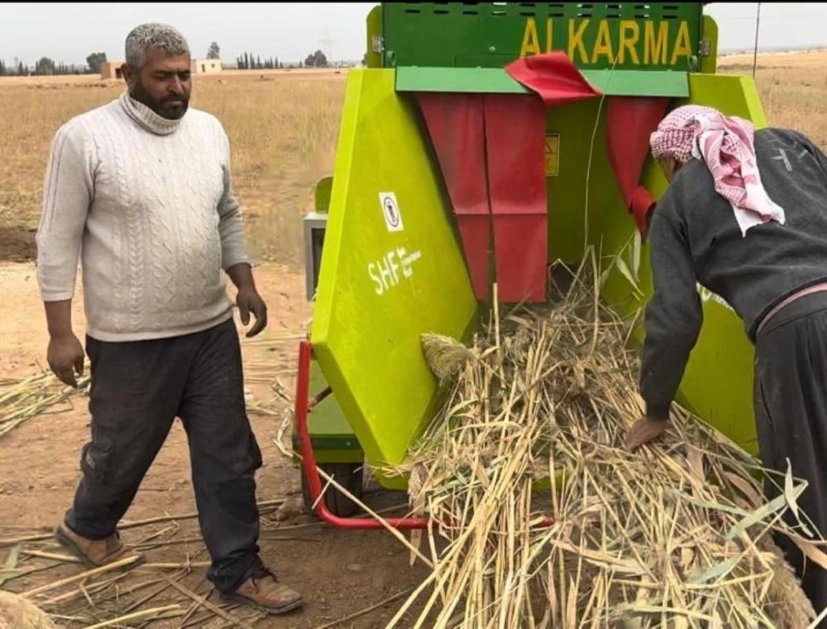 Ibrahim (left) uses the grinder provided by Action Against Hunger.