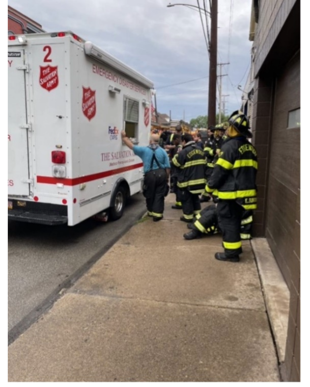 Fire personnel standing by a FedEx and Salvation Army truck