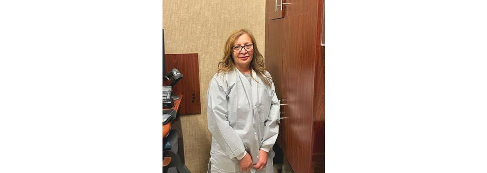 Sandra Reyes wearing a white coat, stood near a cupboard