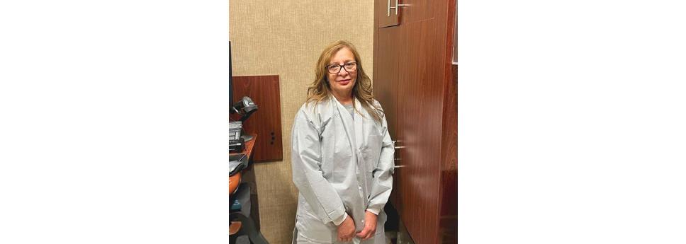 Sandra Reyes wearing a white coat, stood near a cupboard 