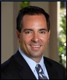 Santiago Arbelaez smiling at the camera, wearing a suit and tie.