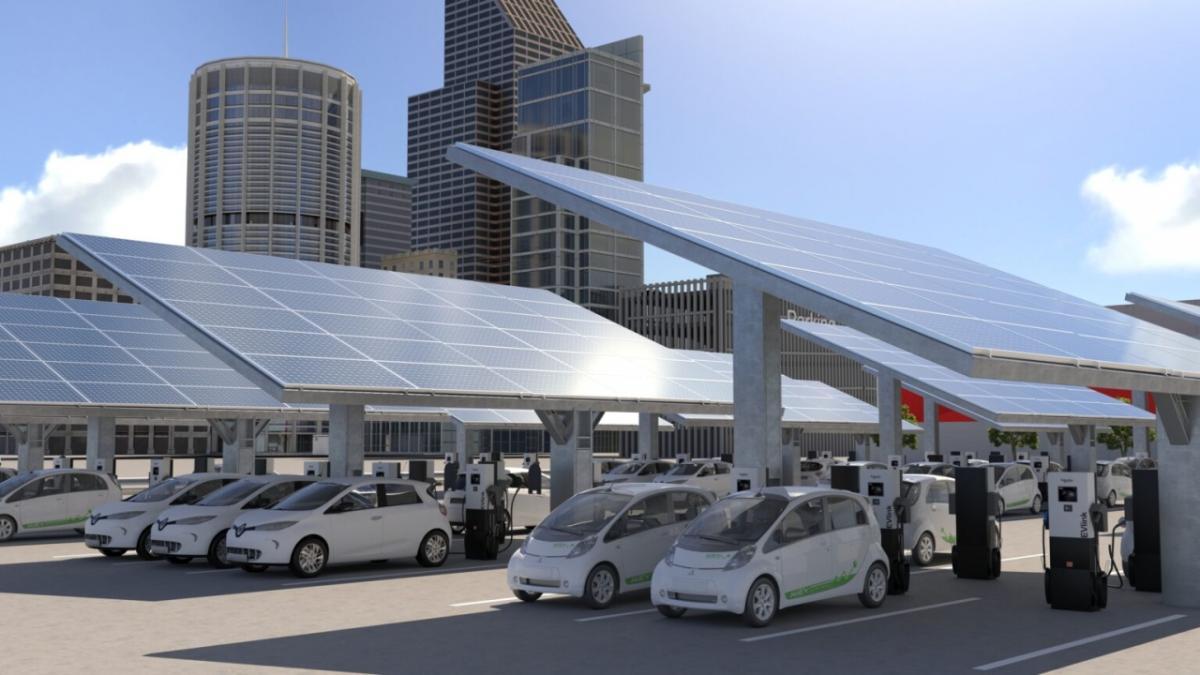 Electric cars pictured below solar panels and next to charging stations 