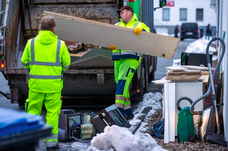 A waste management company throws old furniture boards into a garbage truck. JENS BÜTTNER—PICTURE ALLIANCE/GETTY IMAGES Men throwing old furniture boards into a garbage truck.