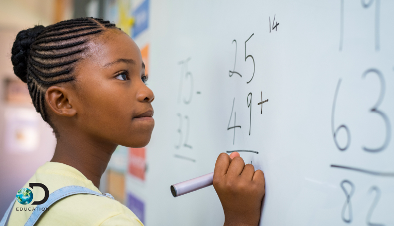 a young girl doing a math equation on the white board