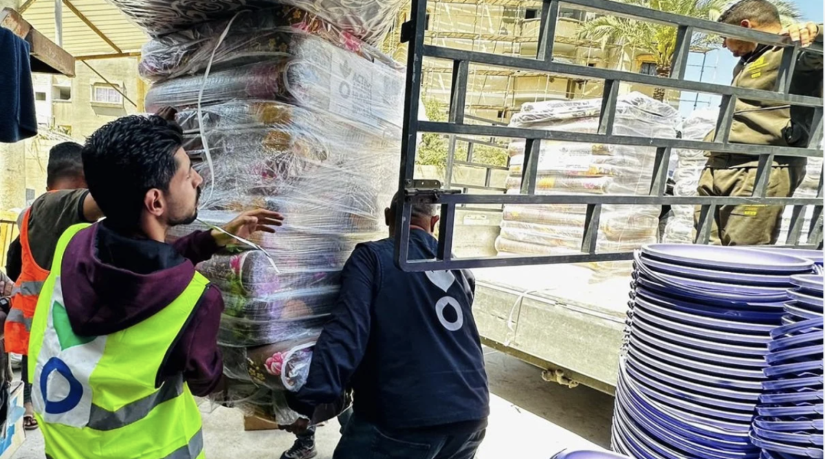 Action Against Hunger is responding in Gaza, Lebanon, and the West Bank. Three people moving heavy supplies onto a truck