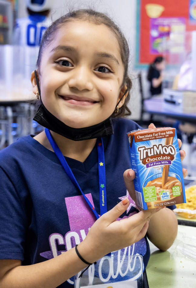 smiling child holding a container of milk