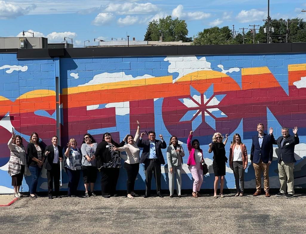 Rural LISC, Grow South Dakota and Wells Fargo celebrate the launch of Rural Connect in Sisseton, SD, improving digital access in rural and native communities. Group of people stand in front of a large wall mural in Sisseton, South Dakota