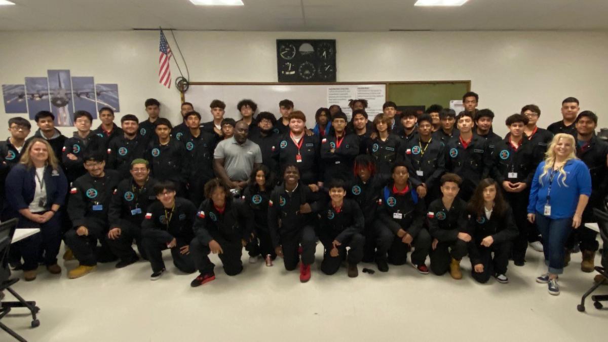 A group of students and adults posed in a classroom.