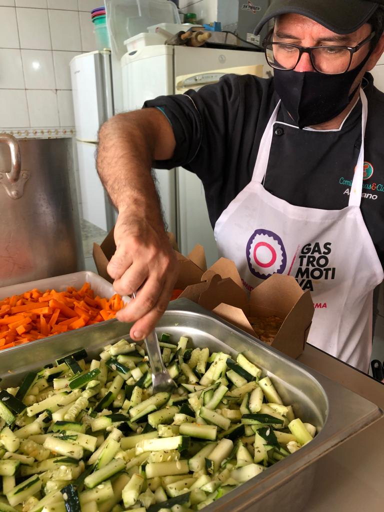 The Solidarity Kitchen program created by the Brazilian nonprofit Gastromotiva serves food-insecure populations through a network of community-based kitchens. Inside a kitchen, a man stirs fresh food in a large metal vessel.