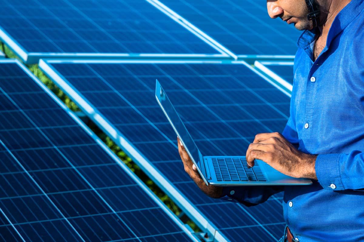 Person using laptop in front of solar panels