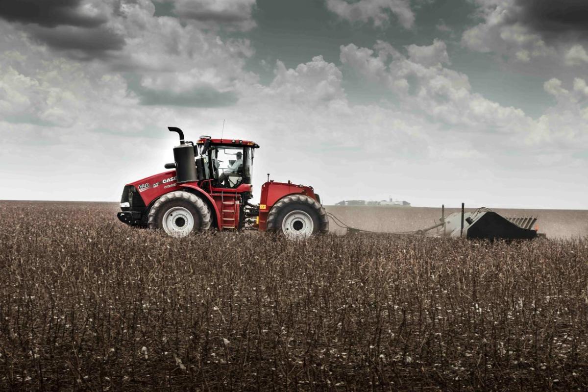 A large farm tractor harvesting crops in a field.