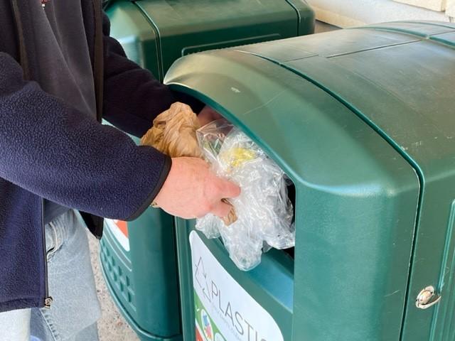 Person placing flexible plastics into a store drop-off bin for recycling.