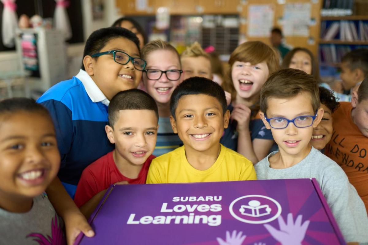 Group of young students holding a box reading, "Subaru loves Learning"