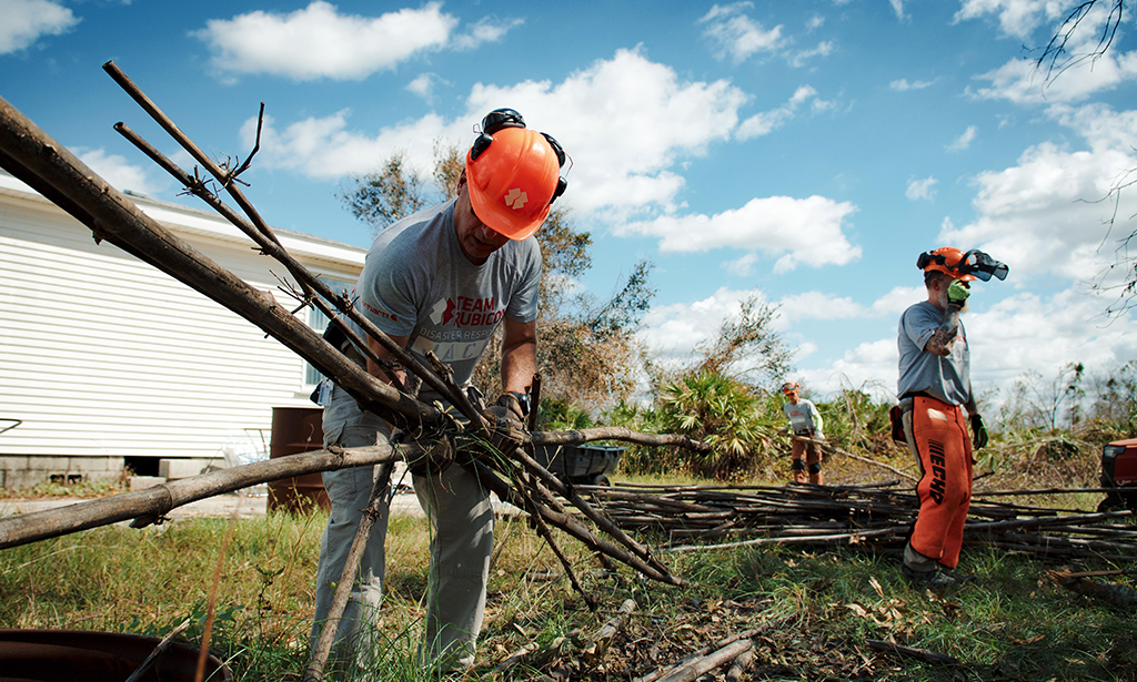 Three people in orange hardhats cleaning up debris