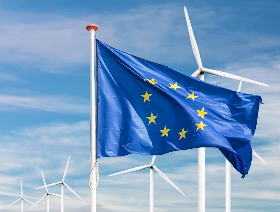 Get ready for new sustainability standards for companies operating in the European Union EU flag flying in front of wind turbines
