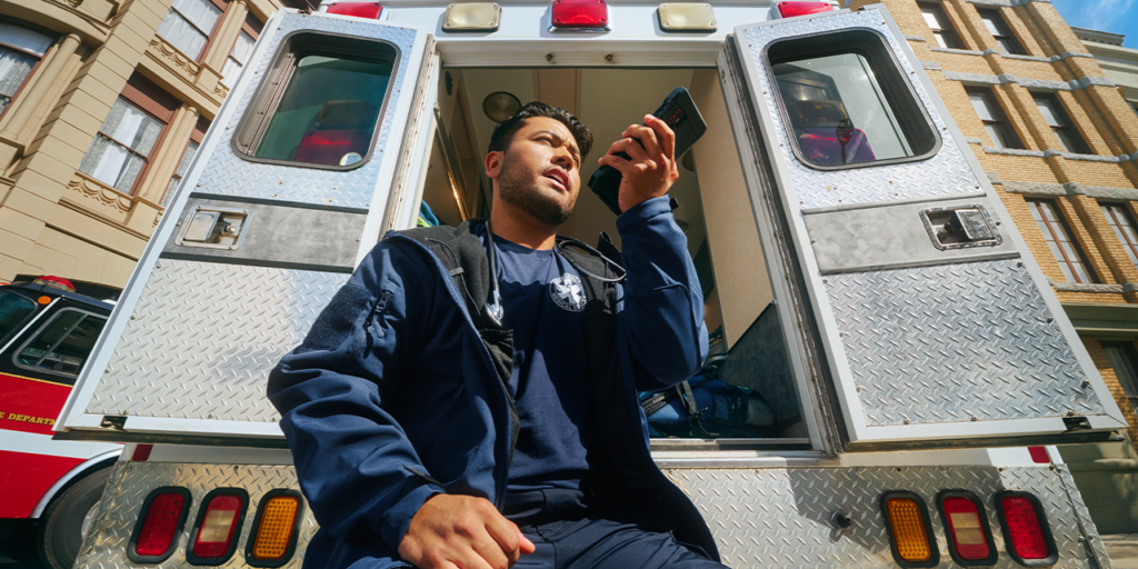 person sitting outside ambulance speaking on phone
