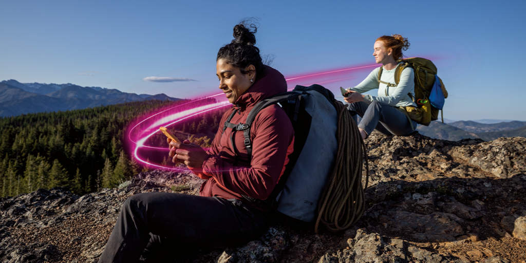 Two people looking at phones on a mountaintop