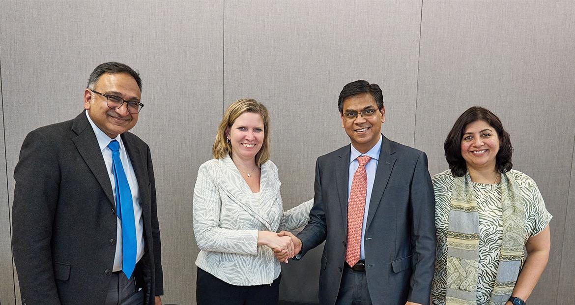 Four people smiling and shaking hands