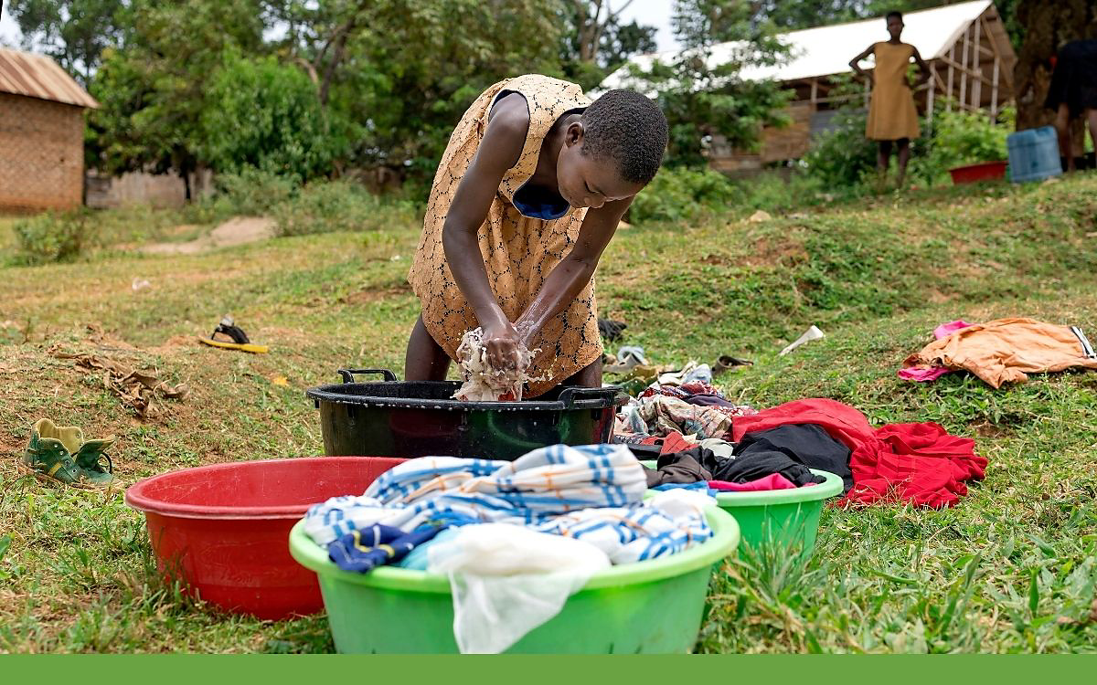 Girl hand washing clothes out of doors