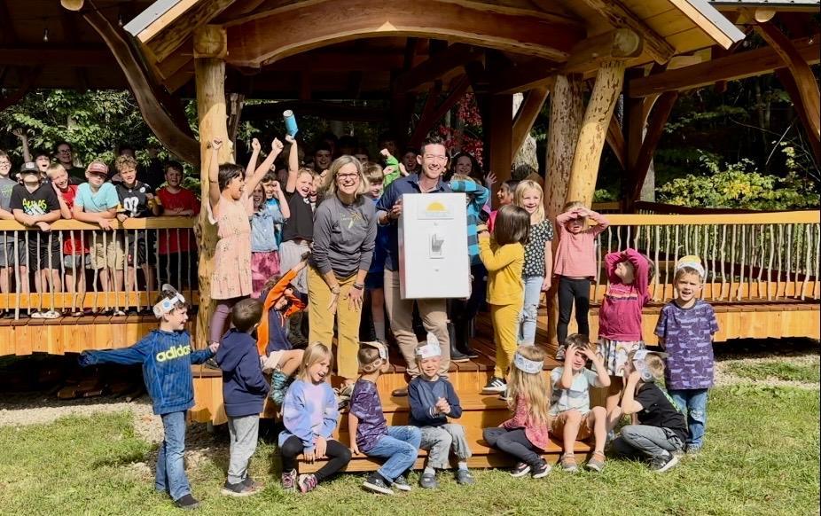 Students cheer as adults flip a life-size light switch at outdoor classroom