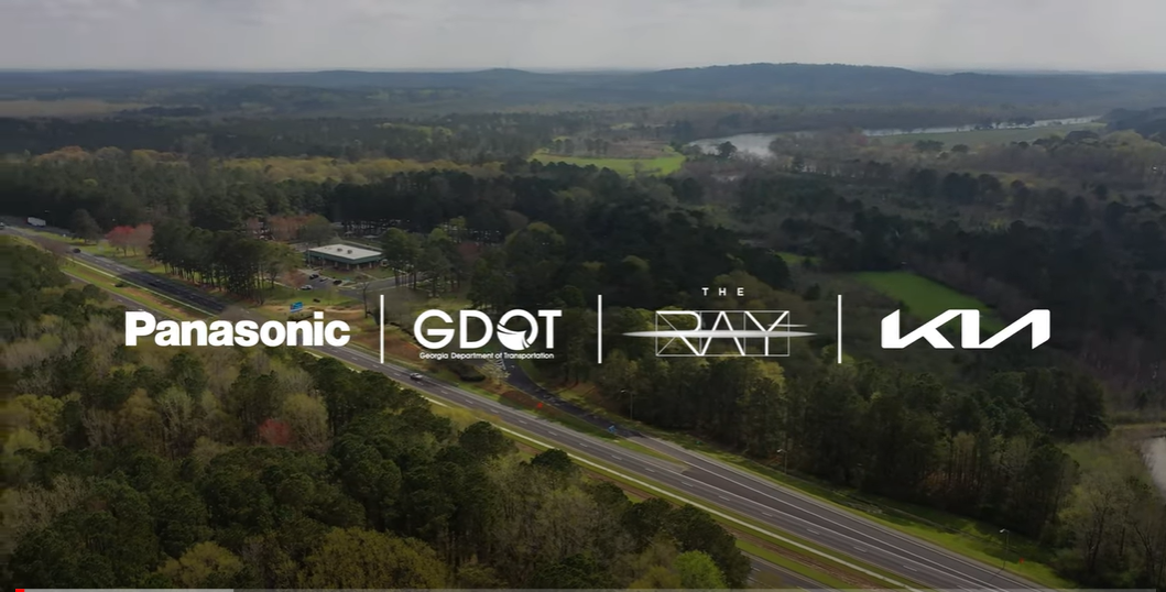 Panasonic logo, GDOT logo, The RAY logo, and Kia Logo overlayed over an aerial view of a highway. 
