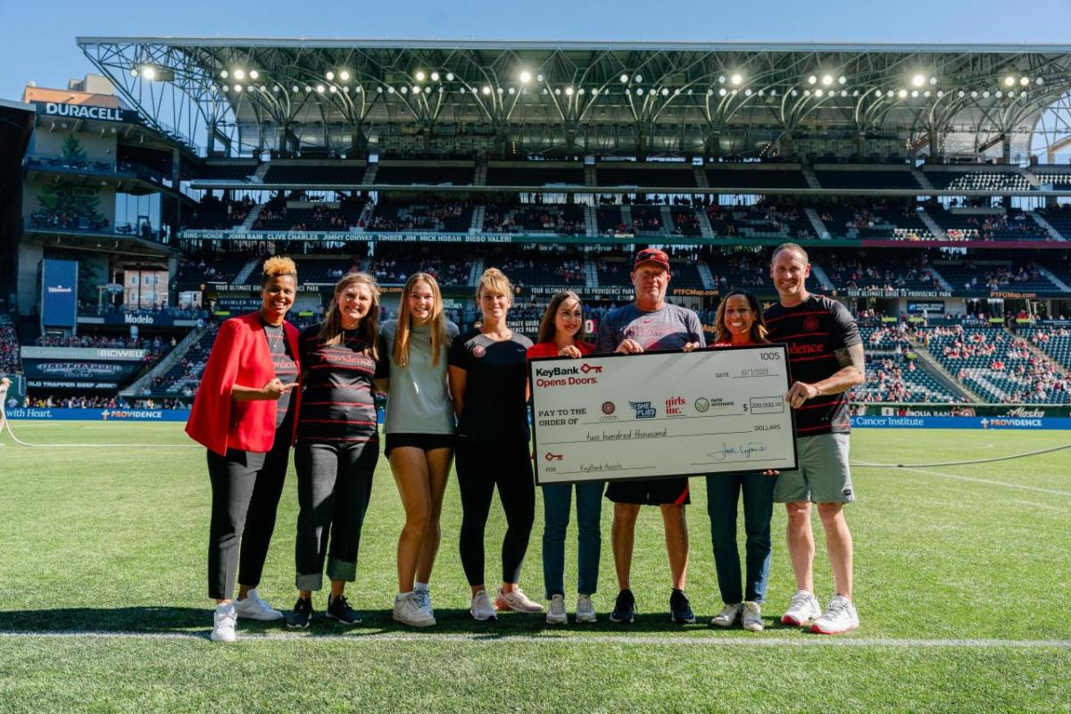 People stood on a soccer pitch holding a cheque 