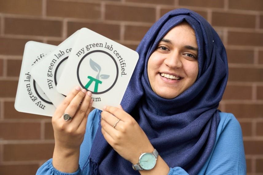 Woman holding stickers that say, "My Green Lab Certified"