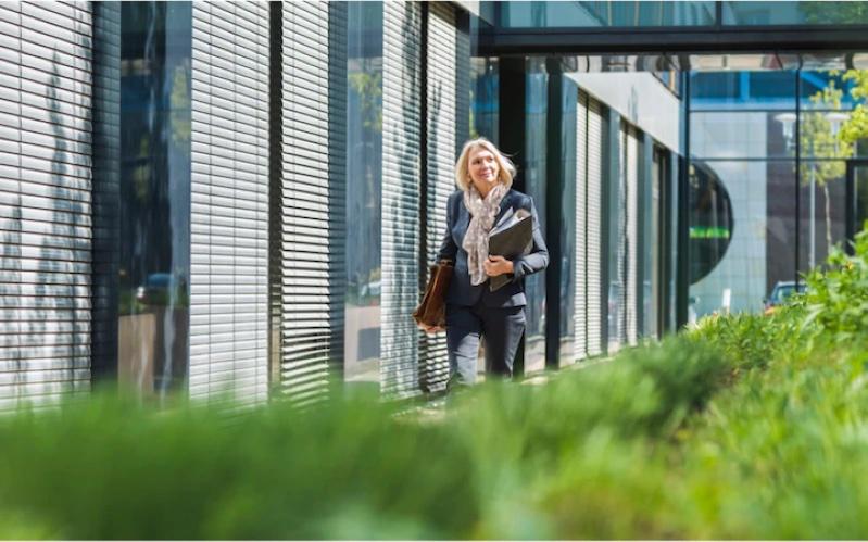 Woman on a college campus walking next to a building.