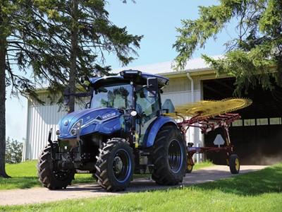 Blue tractor parked on pavement with trees either side