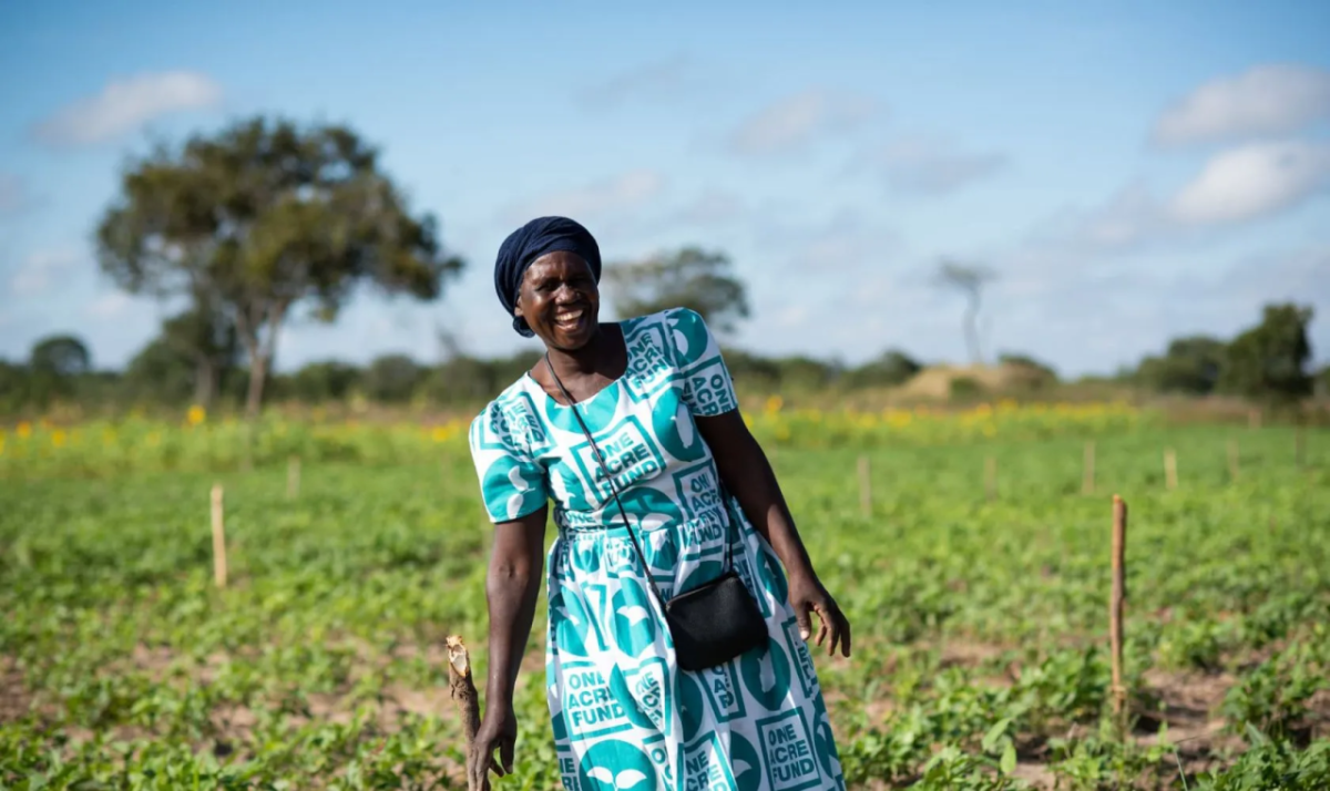 woman in a blue-green dress standing in a green field