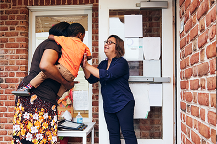 woman holding small child passing off to other woman