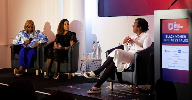 Three people seated on a stage, talking