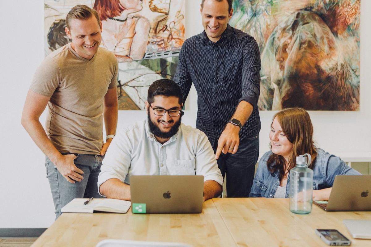 Four coworkers at a table working with laptops.