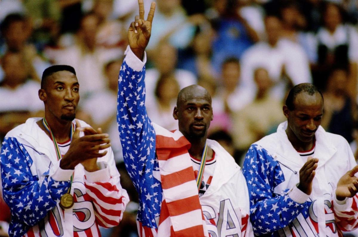 three athletes in USA uniform. medals around their necks. Spectators in the stands behind them.