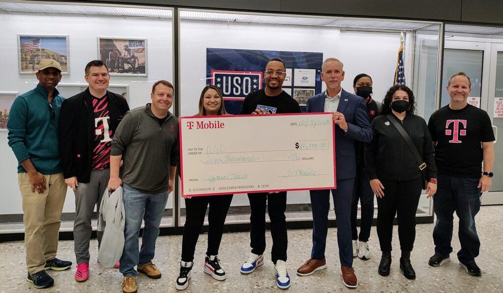 A group of people posed with a large check. USO sign behind them.