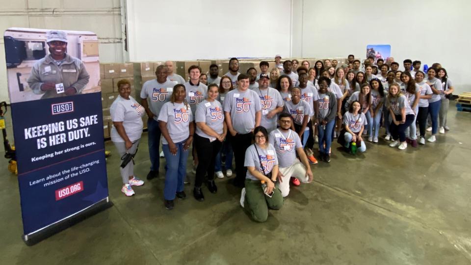 Group posed in a large space, a USO sign to the side.