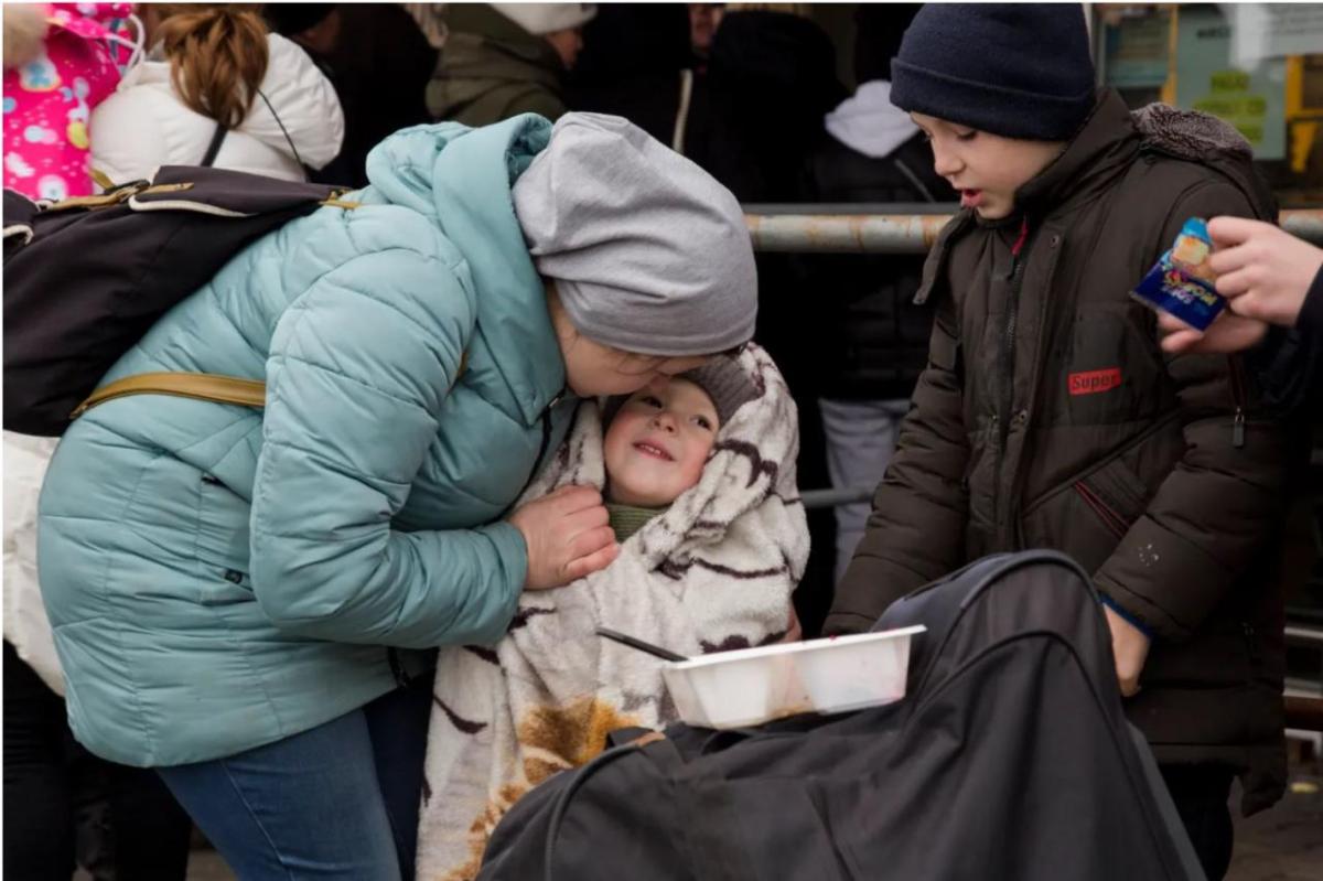 A mother plays with and puts a cover on her son on the way between Medyka and Przemyśl in Poland. (Photo by Oscar Castillo for Direct Relief)