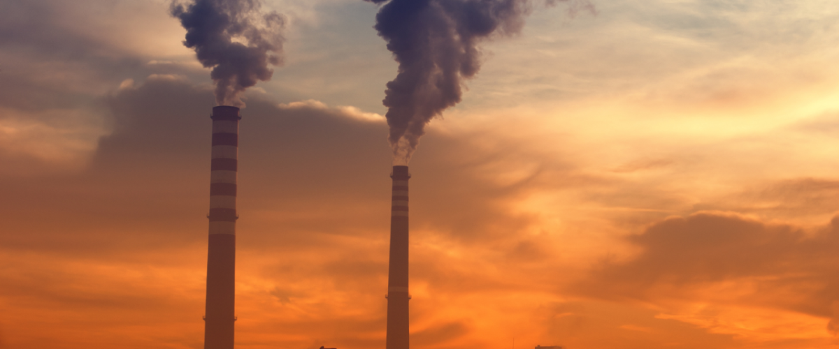 Industrial smoke pumped into a sunset, cloudy sky