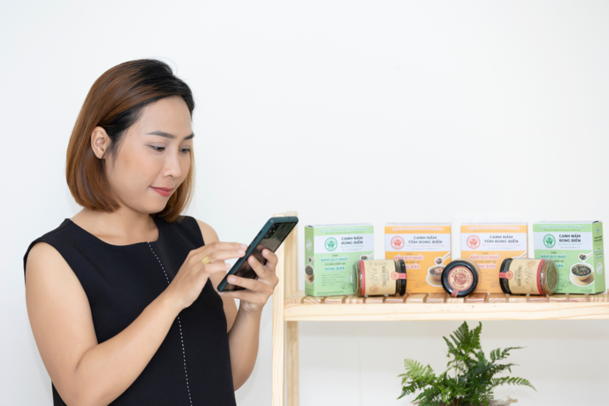 A person using a cell phone, a shelf of products on the right.