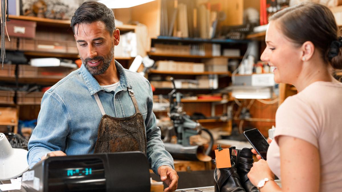 Veteran business owner shown ringing up a sale in his shop.