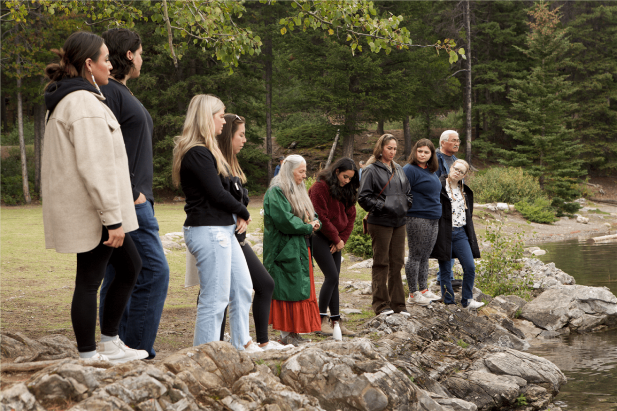 Veronica and others standing at a river bank looking out.