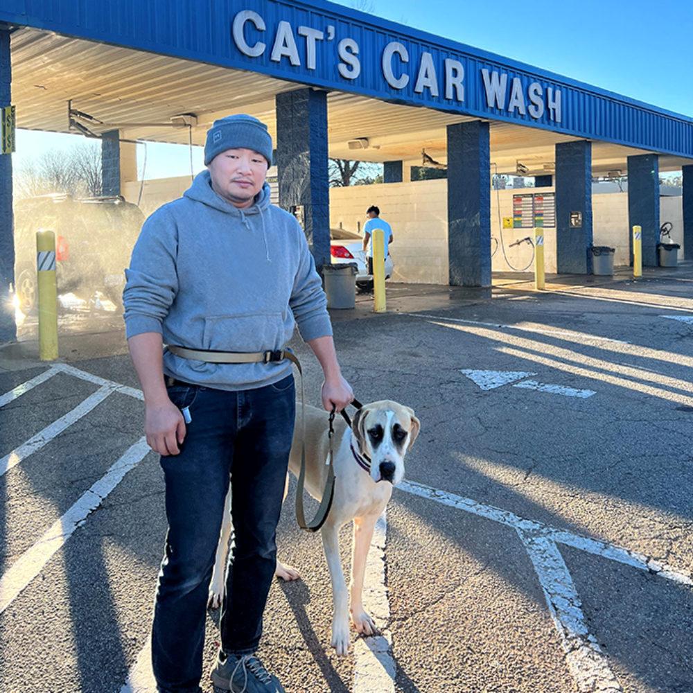 Man stands in front of car wash with his dog