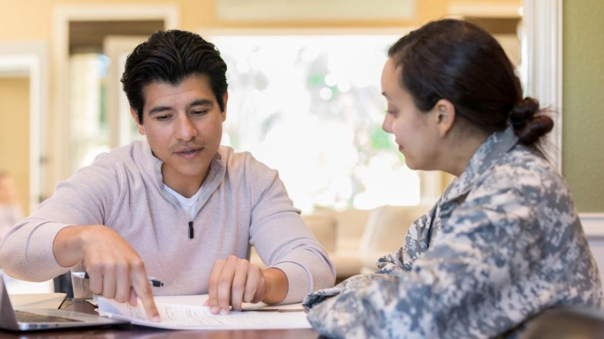 mentor helps a veteran in gray combat fatigues with paperwork