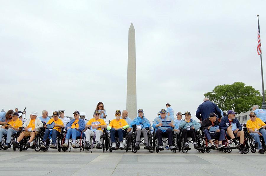 A line of people in wheelchairs and others behind them in front of the washington monument