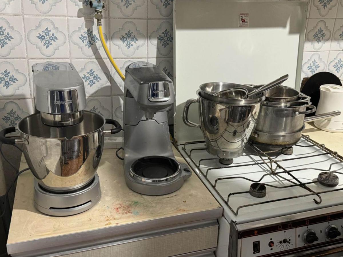Silver mixers and bowls on a counter and stovetop.