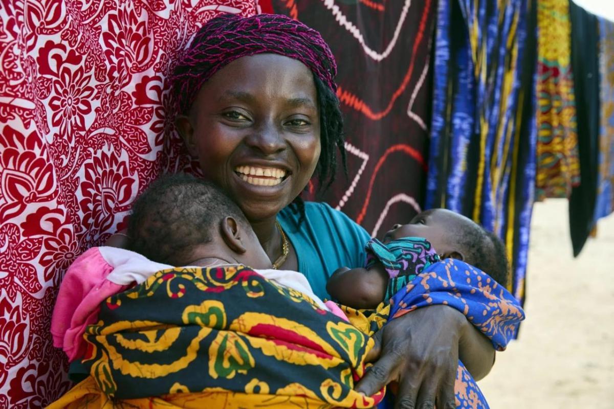 Smiling woman holds her two small children.